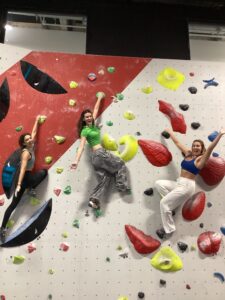 3 women climbing a bouldering wall.